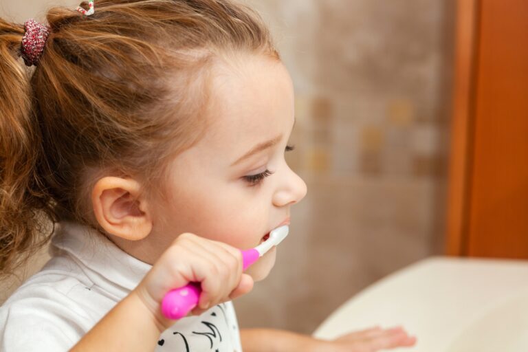 Cute little girl cleaning tooth with brush.